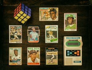 Vintage baseball cards including Roberto Clemente, Rickey Henderson, Hank Aaron, Nolan Ryan, Bo Jackson, and more displayed on a dark wood surface